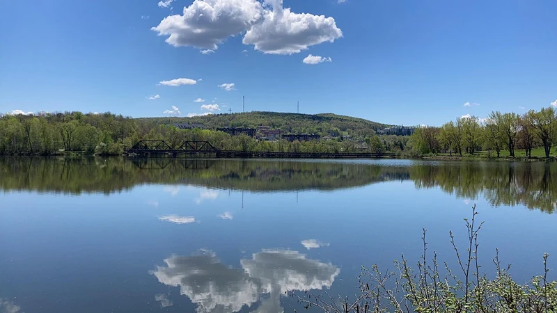 Le lac des Nations à Sherbrooke, ses rives boisées et les reflets du ciel