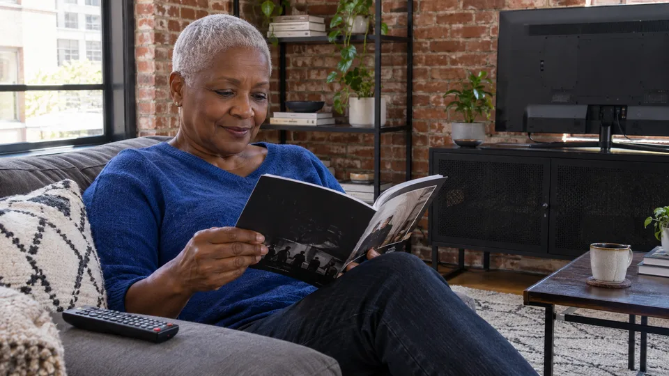 A reader consults a film booklet with her remote nearby